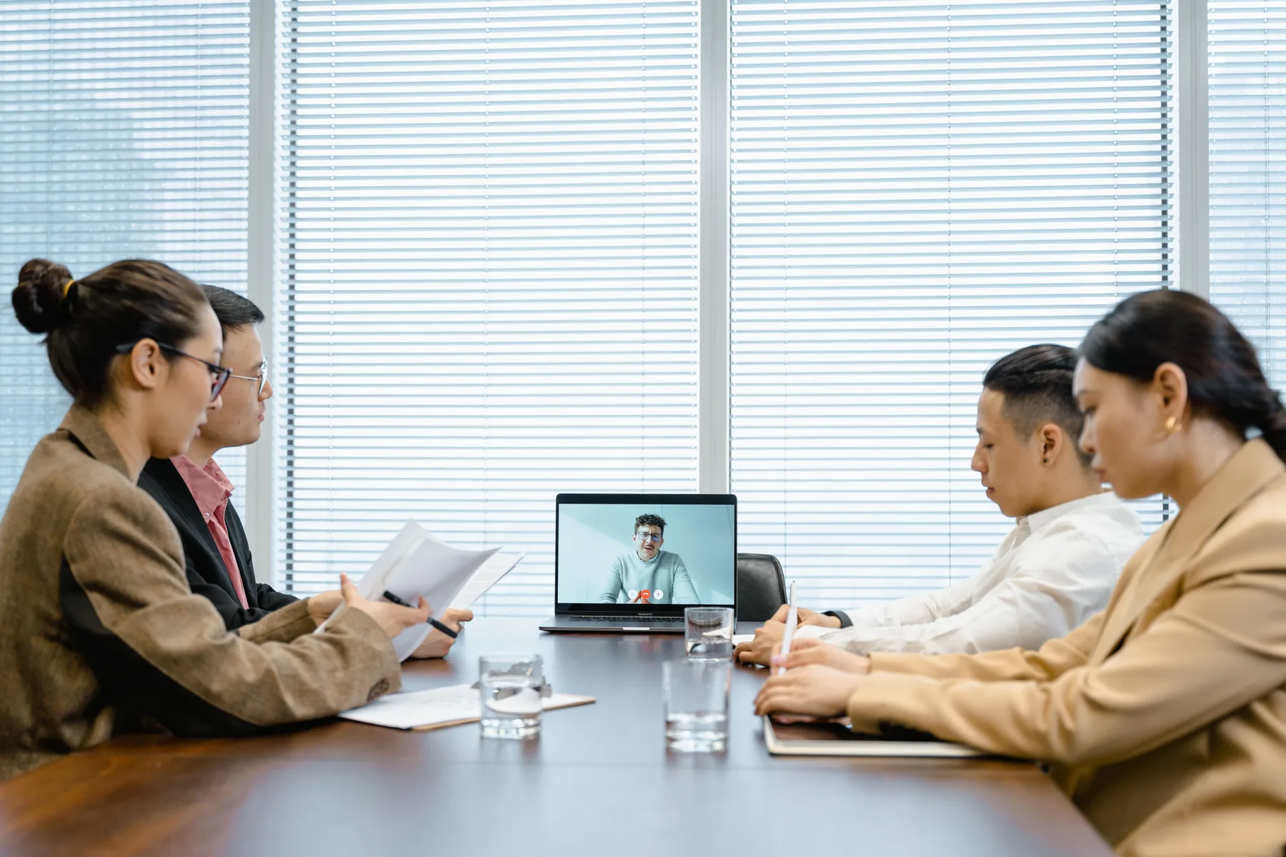 Professional team holding a hybrid meeting with a remote colleague on screen.
